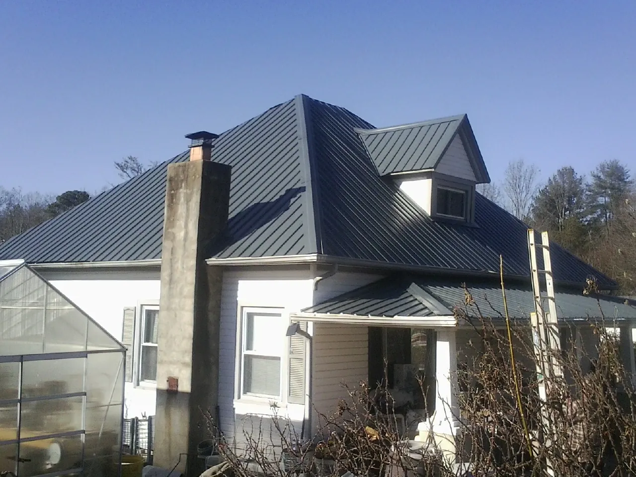 Dark blue standing seam metal roof on a white farmhouse with dormer — Slate & Tile Roof Repair by Roofing Brothers in Macon