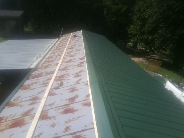 Old rusted panels beside newly installed green metal roofing — Wind Damage Roof Repair by Roofing Brothers in Macon
